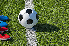 Soccer football background. Soccer ball and two pair of football sports shoes on artificial turf soccer field